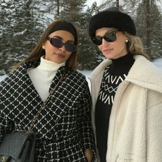 Two women dressed in black and white winter accessories.