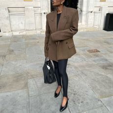 Marilyn Nwawulor-Kazemaks wears a brown blazer, leggings, and black slingback flats.