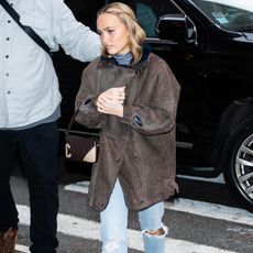 Lily-Rose Depp is seen in Midtown on December 17, 2024 in New York City wearing a leather barn coat, Levi's jeans, socks, and loafers. 