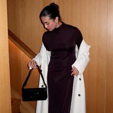 Photo of influencer wearing dark brown mock-neck dress with white trench coat and matching black bag.