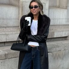 woman in faux-fur black coat, jeans, gloves, and black bag