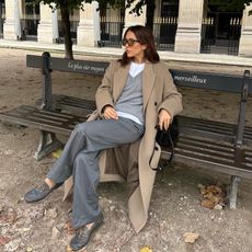 Fashion influencer @deborabrosa sitting on a park bench in Paris wearing the controversial leather boat shoe trend.